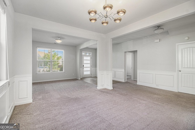 2113 Dodson Woods Dr, Fairburn, GA 30213 - unfurnished living room with carpet, a decorative wall, wainscoting, and an inviting chandelier