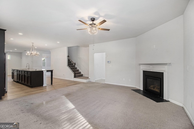 2113 Dodson Woods Dr, Fairburn, GA 30213 - unfurnished living room with baseboards, ceiling fan with notable chandelier, stairs, a fireplace with flush hearth, and light colored carpet