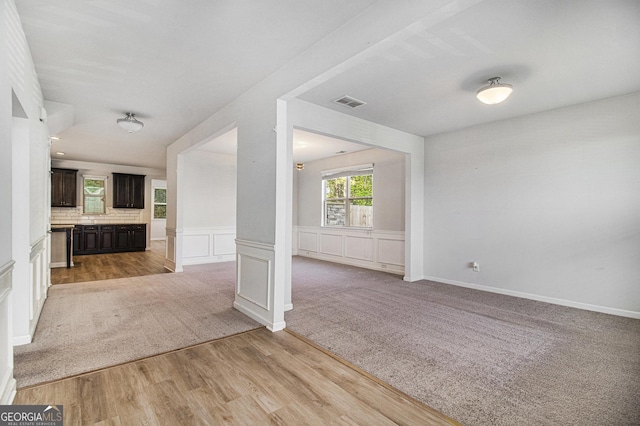 2113 Dodson Woods Dr, Fairburn, GA 30213 - unfurnished living room with a decorative wall, a wainscoted wall, visible vents, light wood finished floors, and light carpet