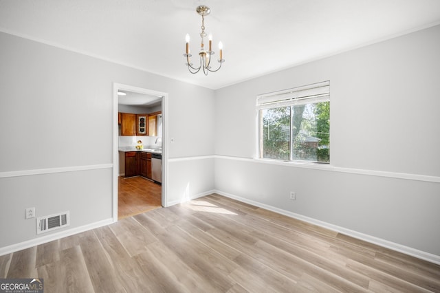 empty room featuring a notable chandelier, baseboards, visible vents, a sink, and light wood-type flooring