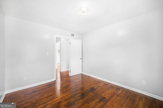 spare room featuring baseboards, visible vents, and wood finished floors