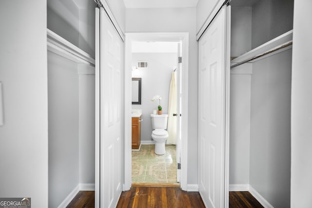 hallway with baseboards, dark wood finished floors, and visible vents