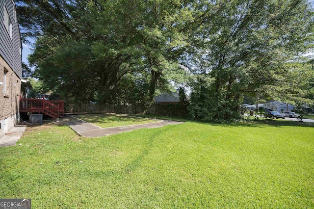 view of yard featuring central AC unit, a deck, and fence