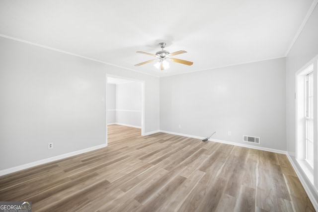 empty room featuring baseboards, crown molding, visible vents, and ceiling fan
