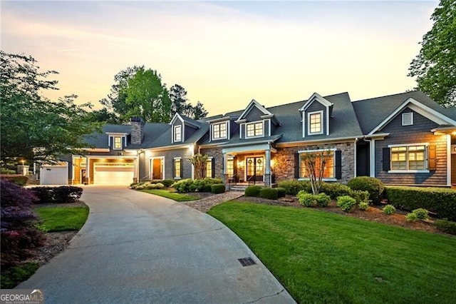 cape cod home with stone siding, driveway, a garage, a front lawn, and a chimney