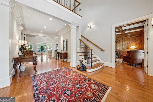 foyer with decorative columns, crown molding, stairway, baseboards, and hardwood / wood-style flooring