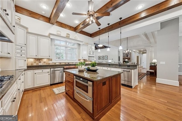 kitchen with a peninsula, a warming drawer, light wood-style flooring, and appliances with stainless steel finishes