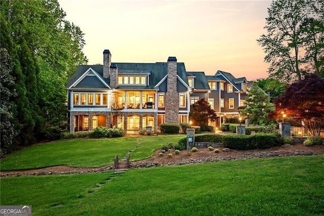 rear view of house featuring a chimney, fence, and a lawn