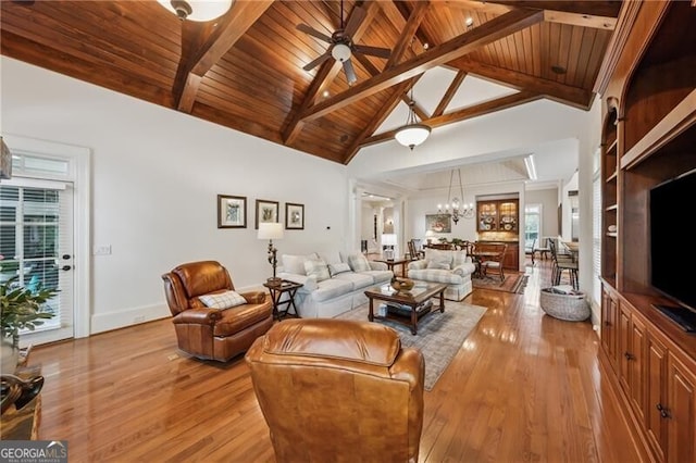 living room featuring a chandelier, beamed ceiling, light wood-type flooring, and plenty of natural light