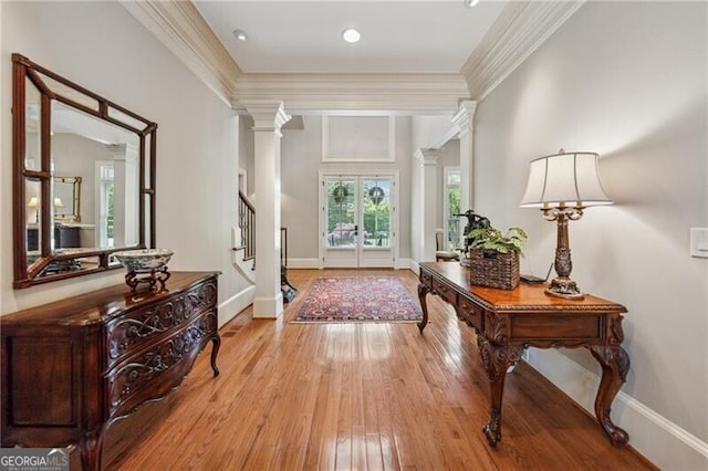 foyer entrance featuring stairs, decorative columns, ornamental molding, wood-type flooring, and baseboards