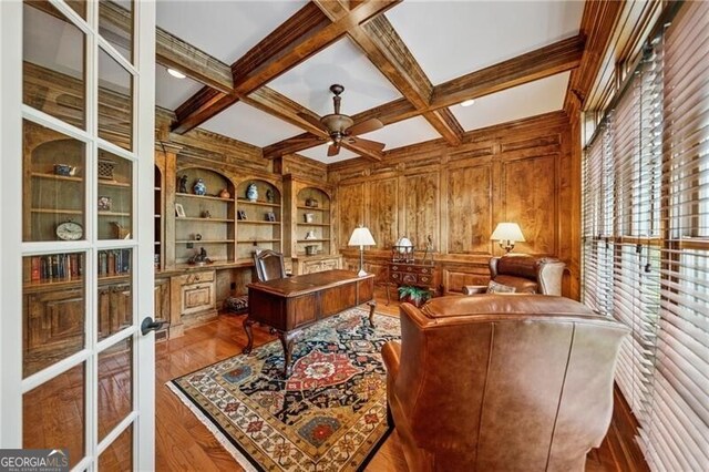 home office with wood walls, french doors, wood finished floors, beam ceiling, and a ceiling fan