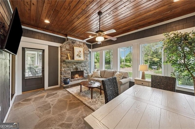 sunroom / solarium with baseboards, a wealth of natural light, stone flooring, and wooden ceiling