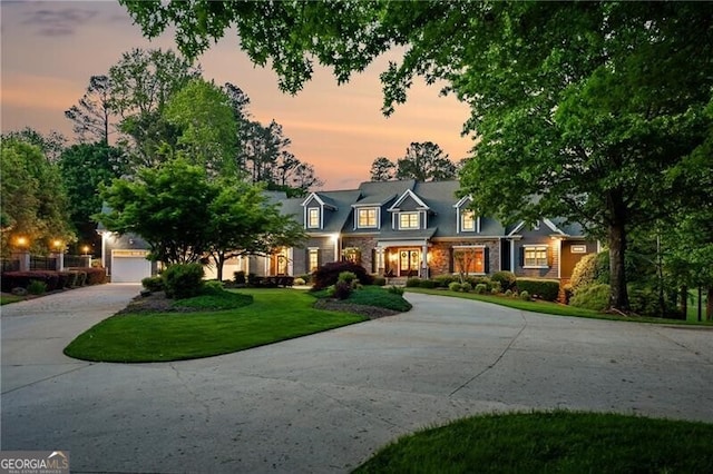 cape cod house featuring a front yard, a garage, and curved driveway