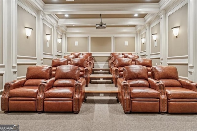 carpeted cinema room with crown molding, beamed ceiling, a decorative wall, and decorative columns