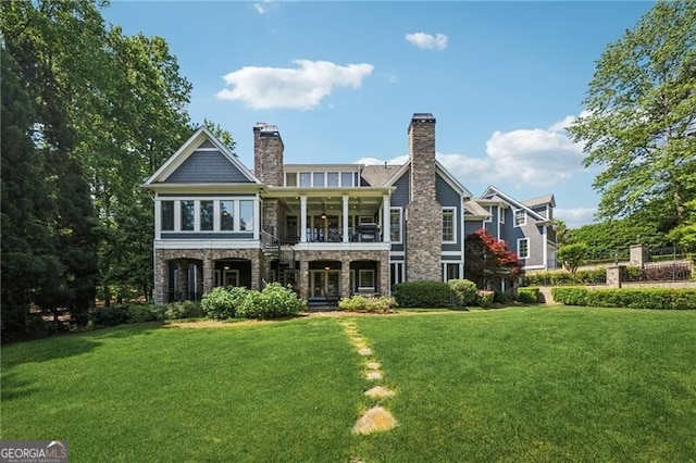 rear view of house featuring a lawn, stone siding, and a balcony
