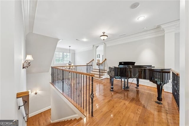 interior space featuring crown molding, an upstairs landing, wood finished floors, and baseboards