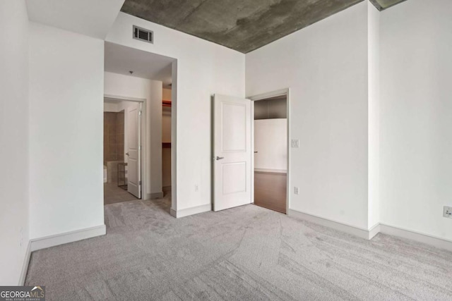 950 W Peachtree St NW Unit 1214, Atlanta, GA 30309 - unfurnished bedroom featuring carpet floors, ensuite bathroom, visible vents, baseboards, and a spacious closet