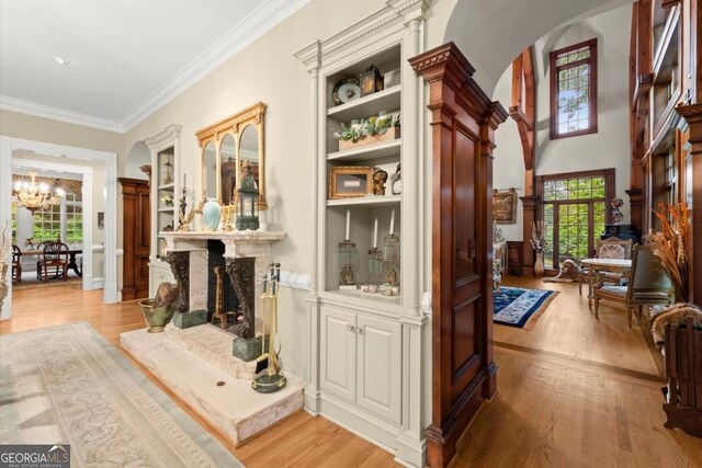 3863 Streamside Dr SE, Marietta, GA 30067 - hall with crown molding, light wood-style flooring, arched walkways, and an inviting chandelier