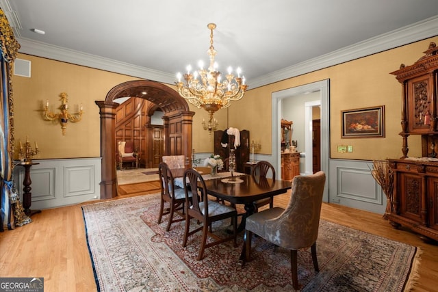 3863 Streamside Dr SE, Marietta, GA 30067 - dining room featuring ornamental molding, a notable chandelier, a decorative wall, and wood finished floors