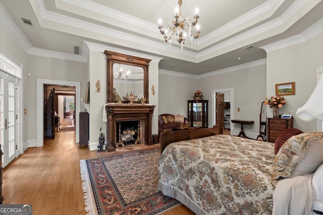 3863 Streamside Dr SE, Marietta, GA 30067 - bedroom featuring a raised ceiling, light wood-style floors, a fireplace, and a chandelier