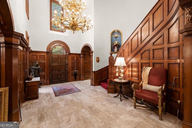 3863 Streamside Dr SE, Marietta, GA 30067 - entrance foyer featuring a decorative wall, a wainscoted wall, a towering ceiling, arched walkways, and a notable chandelier