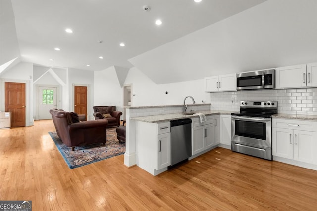 3863 Streamside Dr SE, Marietta, GA 30067 - kitchen featuring a sink, a peninsula, lofted ceiling, light stone counters, and appliances with stainless steel finishes