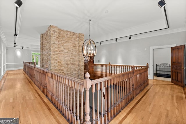 3863 Streamside Dr SE, Marietta, GA 30067 - hallway with an inviting chandelier, rail lighting, crown molding, wood finished floors, and an upstairs landing