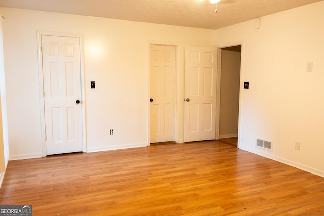 unfurnished bedroom with light wood finished floors, visible vents, and baseboards