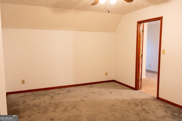 spare room with a textured ceiling, baseboards, carpet flooring, ceiling fan, and vaulted ceiling