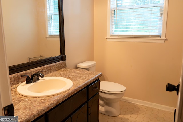 bathroom featuring toilet, baseboards, and vanity