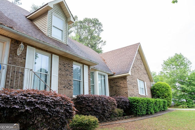view of home's exterior with brick siding and roof with shingles