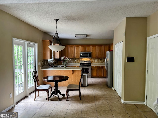 7491 Hilltop Way, Atlanta, GA 30349 - kitchen featuring appliances with stainless steel finishes, decorative backsplash, healthy amount of natural light, a peninsula, and a textured ceiling