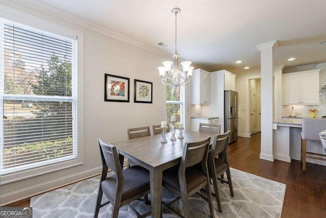 dining room with crown molding, a wealth of natural light, dark wood-style flooring, and a notable chandelier