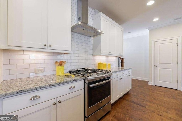 kitchen featuring stainless steel range with gas stovetop, ornamental molding, wall chimney exhaust hood, white cabinets, and baseboards
