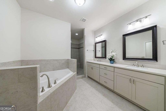 full bath featuring a sink, double vanity, a garden tub, and tiled shower