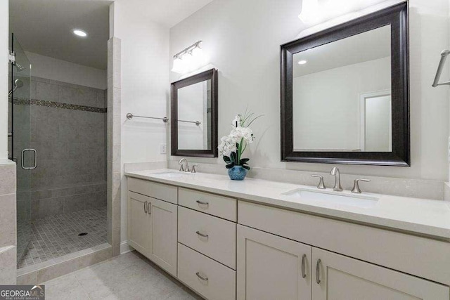 bathroom with a sink, double vanity, a shower stall, and tile patterned flooring