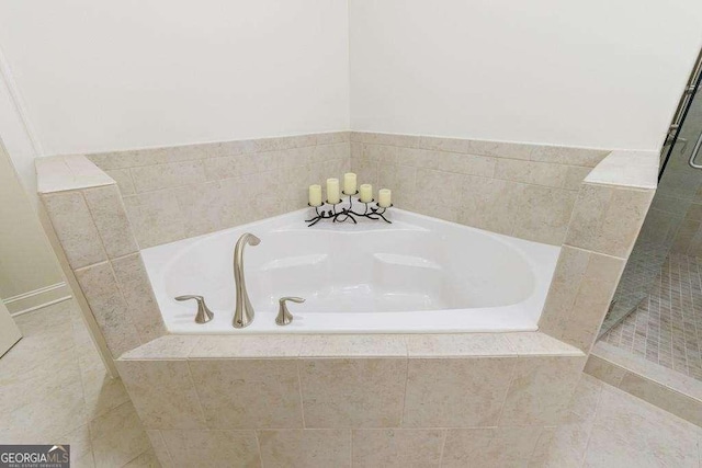 bathroom with a tile shower, tile patterned floors, and a bath