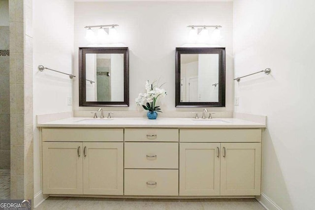 bathroom with a sink, double vanity, baseboards, and tiled shower
