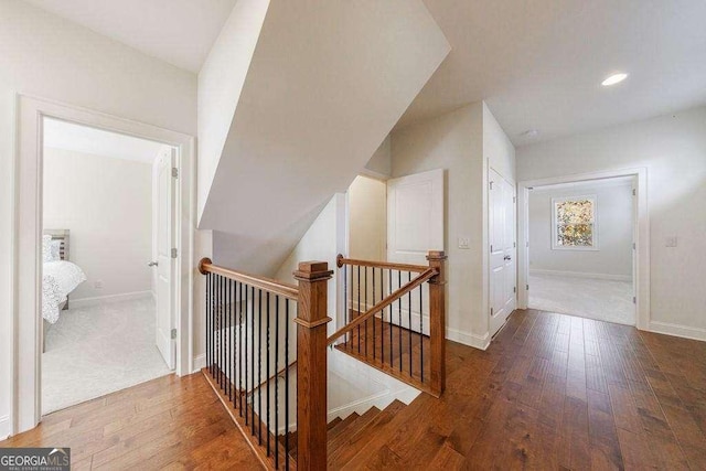 corridor featuring an upstairs landing, baseboards, wood-type flooring, and recessed lighting
