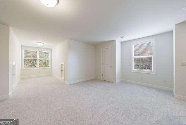 spare room featuring light carpet and baseboards