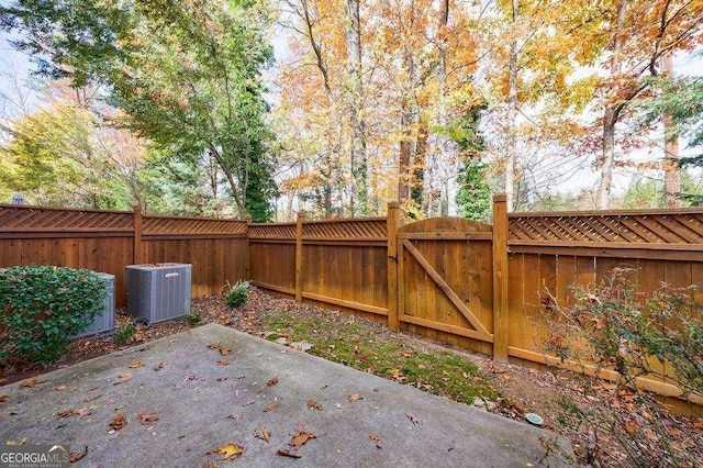exterior space with central AC, a fenced backyard, and a gate