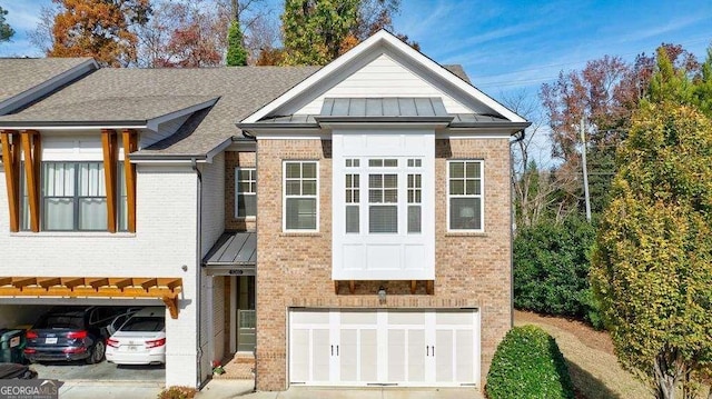 view of front of property with concrete driveway, a standing seam roof, brick siding, and an attached garage