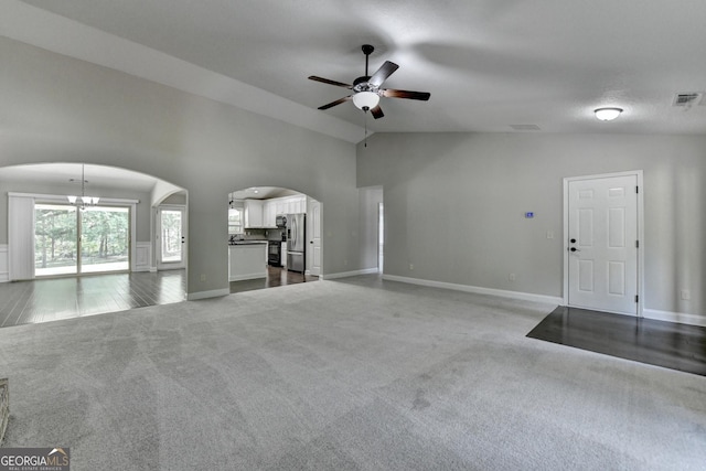 unfurnished living room with ceiling fan with notable chandelier, visible vents, carpet floors, arched walkways, and baseboards