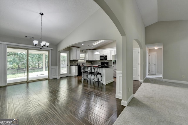 living room featuring arched walkways, visible vents, an inviting chandelier, and high vaulted ceiling