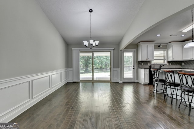kitchen with dark countertops, a chandelier, white cabinets, and vaulted ceiling