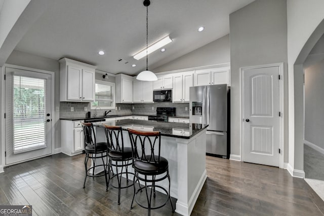 kitchen with lofted ceiling, arched walkways, black appliances, dark countertops, and white cabinets