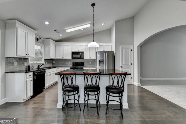 kitchen with dark countertops, visible vents, black appliances, arched walkways, and vaulted ceiling