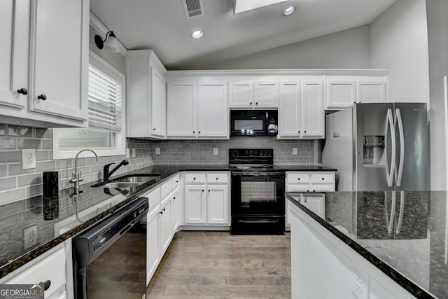 kitchen with visible vents, white cabinetry, vaulted ceiling, black appliances, and dark stone counters