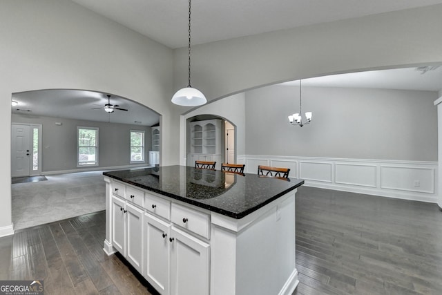 kitchen with ceiling fan with notable chandelier, dark wood finished floors, open floor plan, arched walkways, and a center island