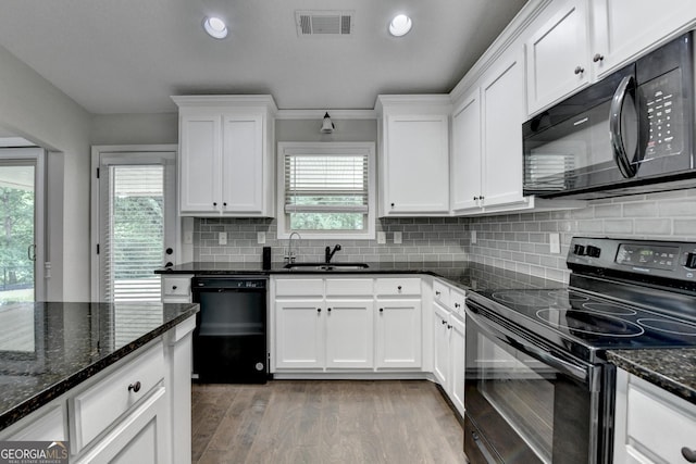 kitchen featuring visible vents, a sink, black appliances, white cabinets, and light wood-type flooring
